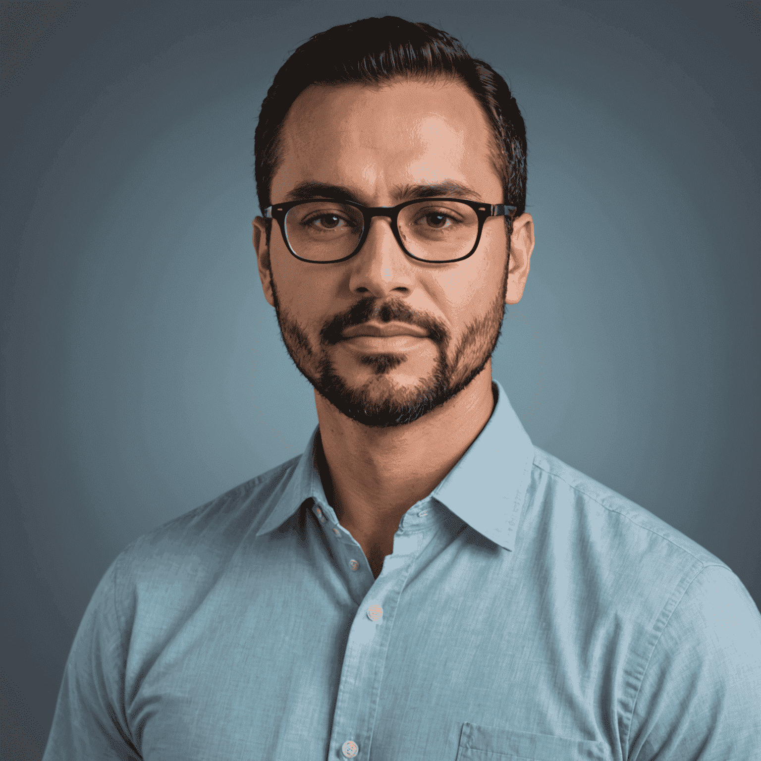 Foto de Carlos Ruiz, coach de bienestar. Un hombre de unos 35 años con barba corta, gafas y expresión serena, vistiendo una camisa azul claro.